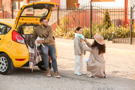 Happy parents with little daughter and cute dog near yellow carの写真素材