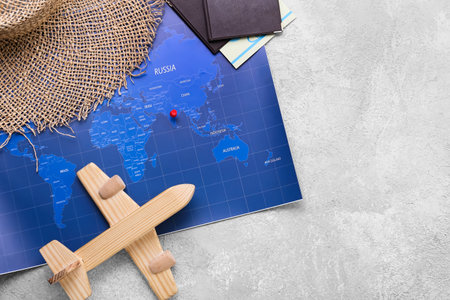 Wicker hat, wooden plane, passports and world map on gray background