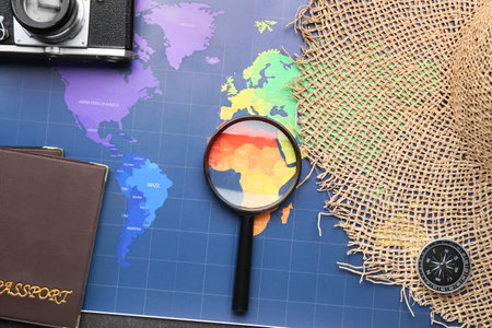 Magnifying glass, photo camera, passports, wicker hat and compass on world mapの写真素材