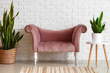Stylish comfortable armchair with houseplants near white brick wall in room
