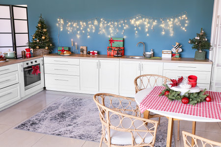 Interior of stylish kitchen with white counters, small Christmas trees and blue wallの写真素材