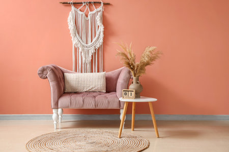 Stylish comfortable armchair with table near pink wall in room