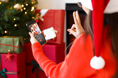 Young woman video chatting with friends at home on Christmas eveの写真素材