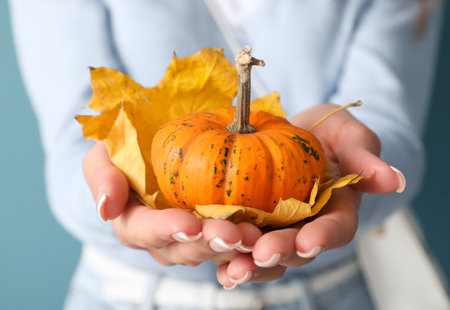 Woman holding pumpkin and autumn leaves, closeupの写真素材