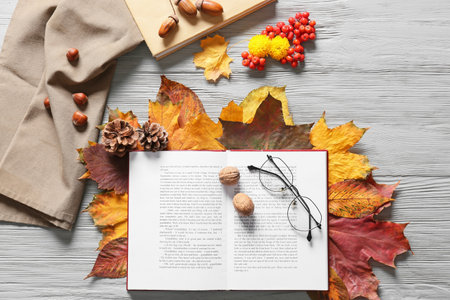 Composition with open book, eyeglasses and beautiful autumn decor on light wooden backgroundの写真素材