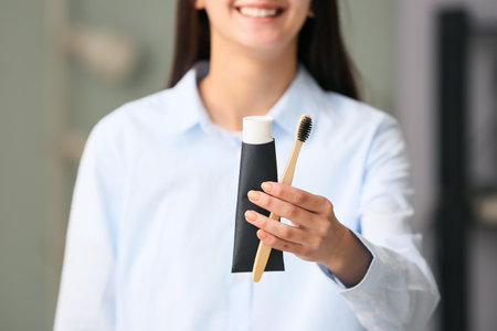 Woman with tube of black tooth paste and bamboo brush at home, closeupの写真素材