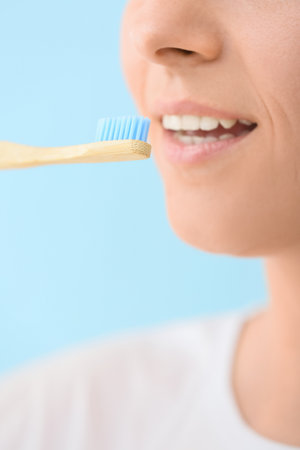Woman with bamboo tooth brush on blue background, closeupの写真素材