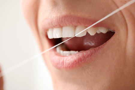 Woman with dental floss on white background, closeup