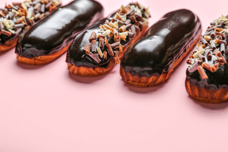 Delicious chocolate eclairs on pink background, closeup