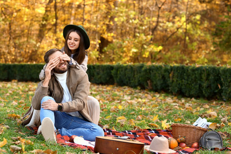 Young woman closing eyes to her beloved in autumn parkの写真素材