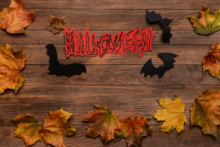 Word Halloween with paper bats and fallen leaves on wooden backgroundの写真素材