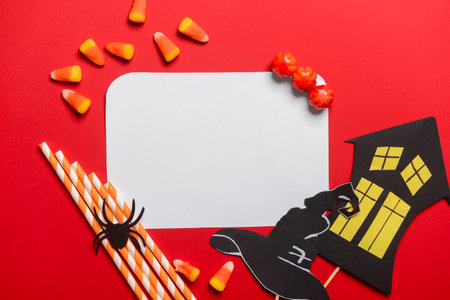 Blank paper sheet with candies and Halloween decor on red backgroundの写真素材