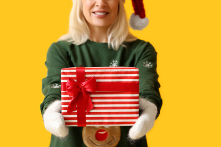 Mature woman with Christmas gift box on color backgroundの写真素材