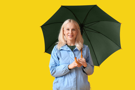 Beautiful mature woman with umbrella on color backgroundの写真素材