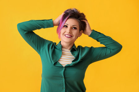 Beautiful woman with short dyed hair on yellow backgroundの写真素材