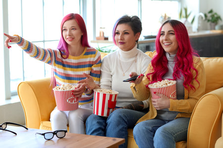 Beautiful women with popcorn watching movie at homeの写真素材