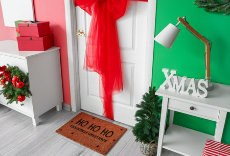 Table with lamp and word XMAS near white door in room decorated for Christmasの写真素材