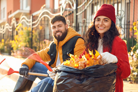 Couple resting after gathering autumn leaves outdoorsの写真素材