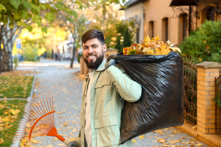 Man gathering autumn leaves outdoorsの写真素材
