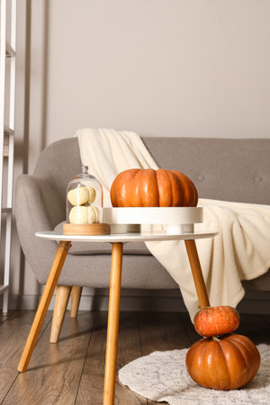 Fresh pumpkins on table and comfortable sofa in roomの写真素材