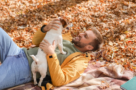 Handsome man with funny Jack Russel terrier in park on autumn dayの写真素材