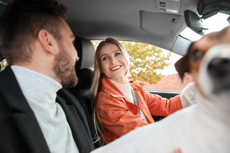 Happy beautiful woman with her boyfriend and cute dog driving car