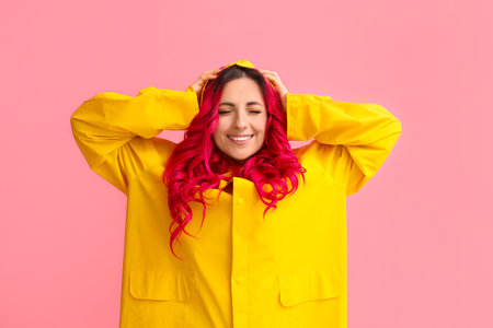 Beautiful woman with bright hair wearing raincoat on color backgroundの写真素材