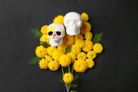 Human skulls for Mexico's Day of the Dead (El Dia de Muertos) and flowers on black background