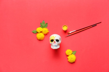 Painted human skull for Mexico's Day of the Dead (El Dia de Muertos) with brushes and flowers on red backgroundの写真素材