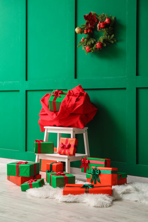 Stepladder with Santa bag and gifts near green wallの写真素材