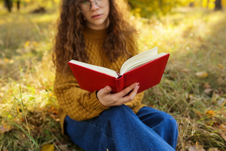 Woman reading book in autumn park, closeupの写真素材