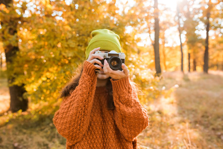 Young woman taking picture in autumn forestの写真素材