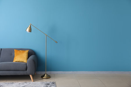 Golden standard lamp and sofa near blue wallの写真素材