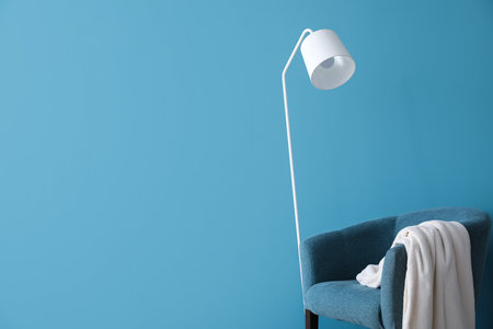 White floor lamp and armchair near blue wallの写真素材