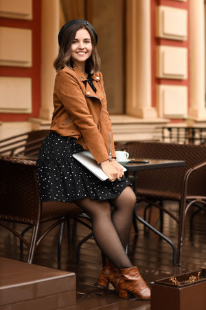 Fashionable woman with modern laptop in street cafeの写真素材