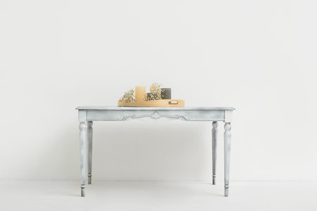 Tray with candles and flowers on table near light wallの写真素材