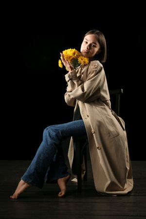 Pretty young woman with bouquet of flowers on black backgroundの写真素材