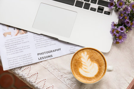 Cup of tasty coffee laptop and newspaper on table in cafeの写真素材
