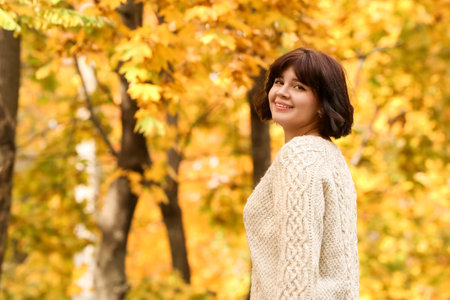Happy brunette woman enjoying sunny day in autumn parkの写真素材