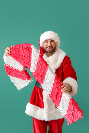 Santa Claus with candy cane pinata on green backgroundの写真素材