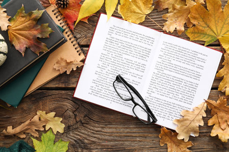 Composition with open book, eyeglasses and autumn leaves on wooden backgroundの写真素材