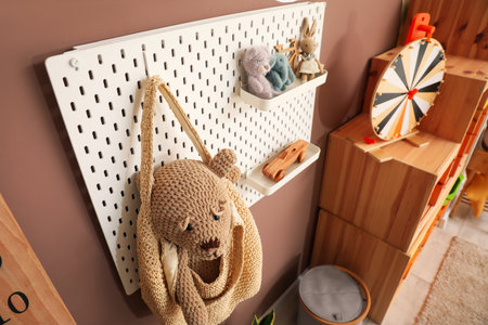 Pegboard with bag and toys hanging on color wall in children's playroomの写真素材