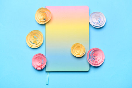 Notebook and paper flowers on color backgroundの写真素材