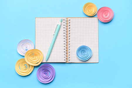 Spiral notebook, pen and paper flowers on color backgroundの写真素材