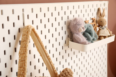 Pegboard with knitted children toys hanging on brown wall, closeupの写真素材