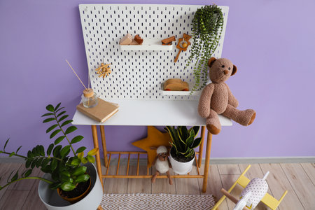 Table with pegboard, toys and houseplants near lilac wallの写真素材