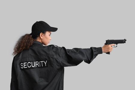 African-American female security guard with gun on light backgroundの写真素材