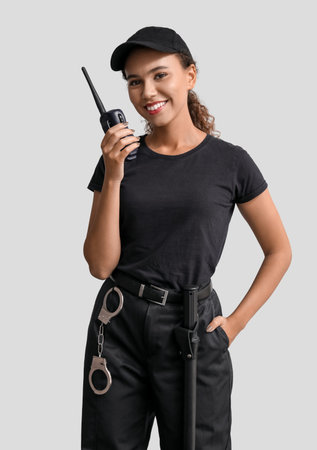 African-American female security guard with radio transmitter on light backgroundの写真素材