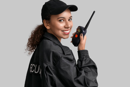 African-American female security guard with radio transmitter on light backgroundの写真素材