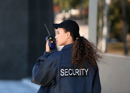 African-American female security guard with radio transmitter near building outdoorsの写真素材